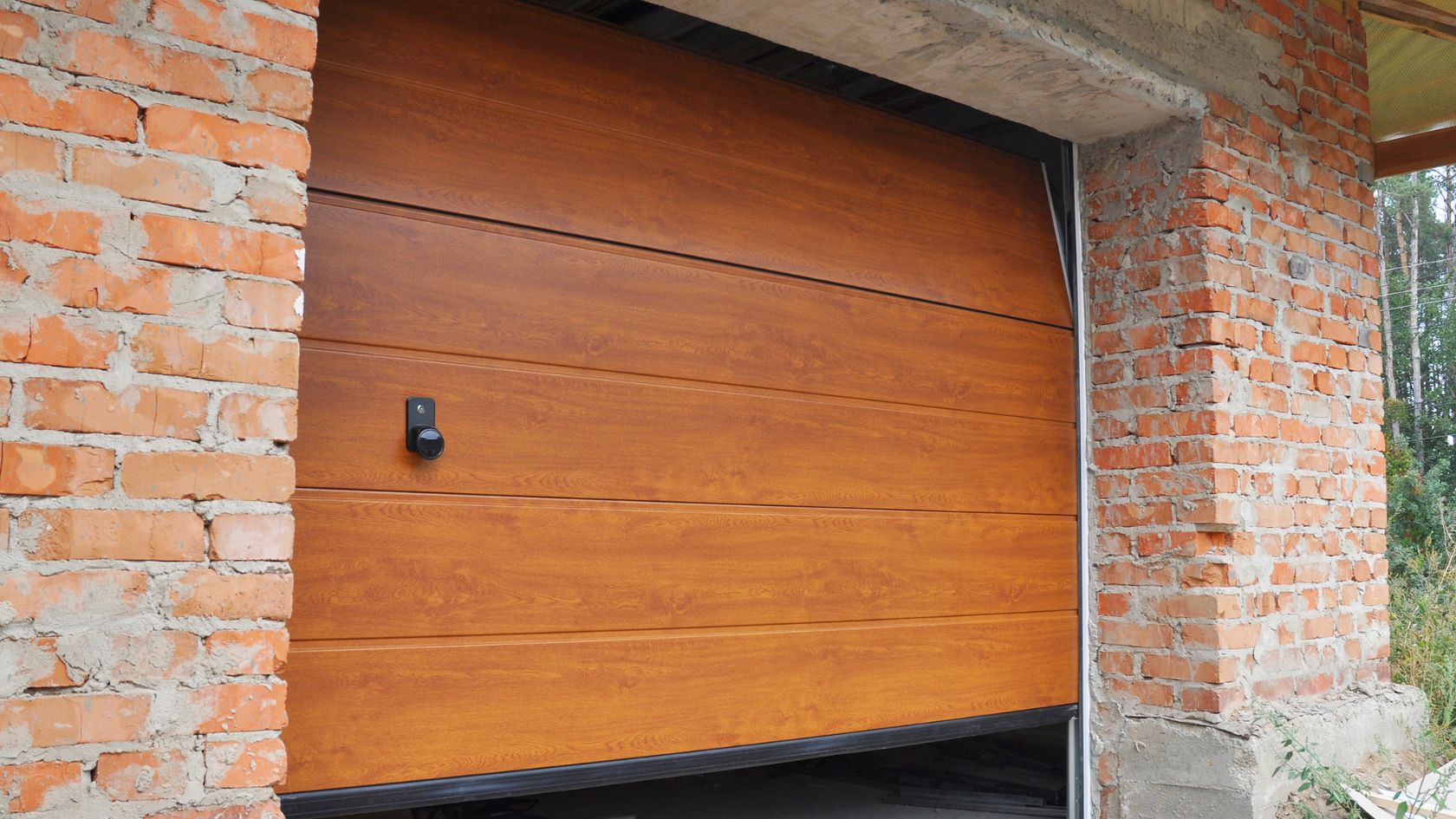 A brown garage door is open on a brick building