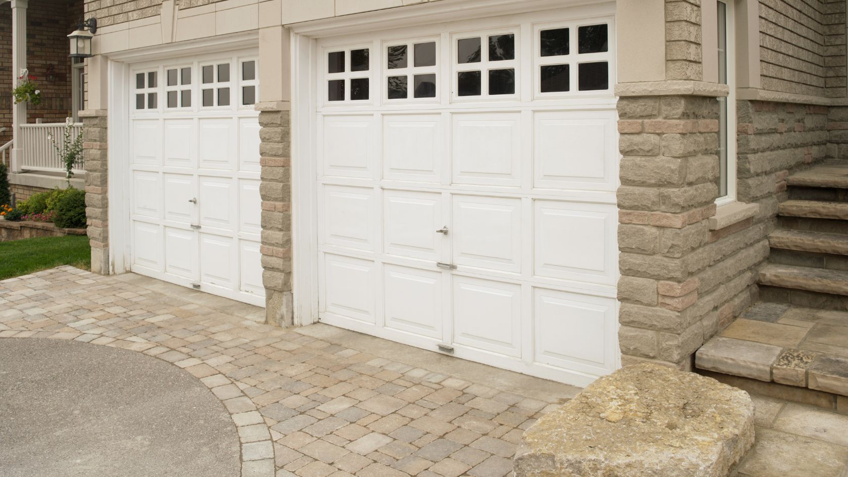 A house with a driveway and two white garage doors