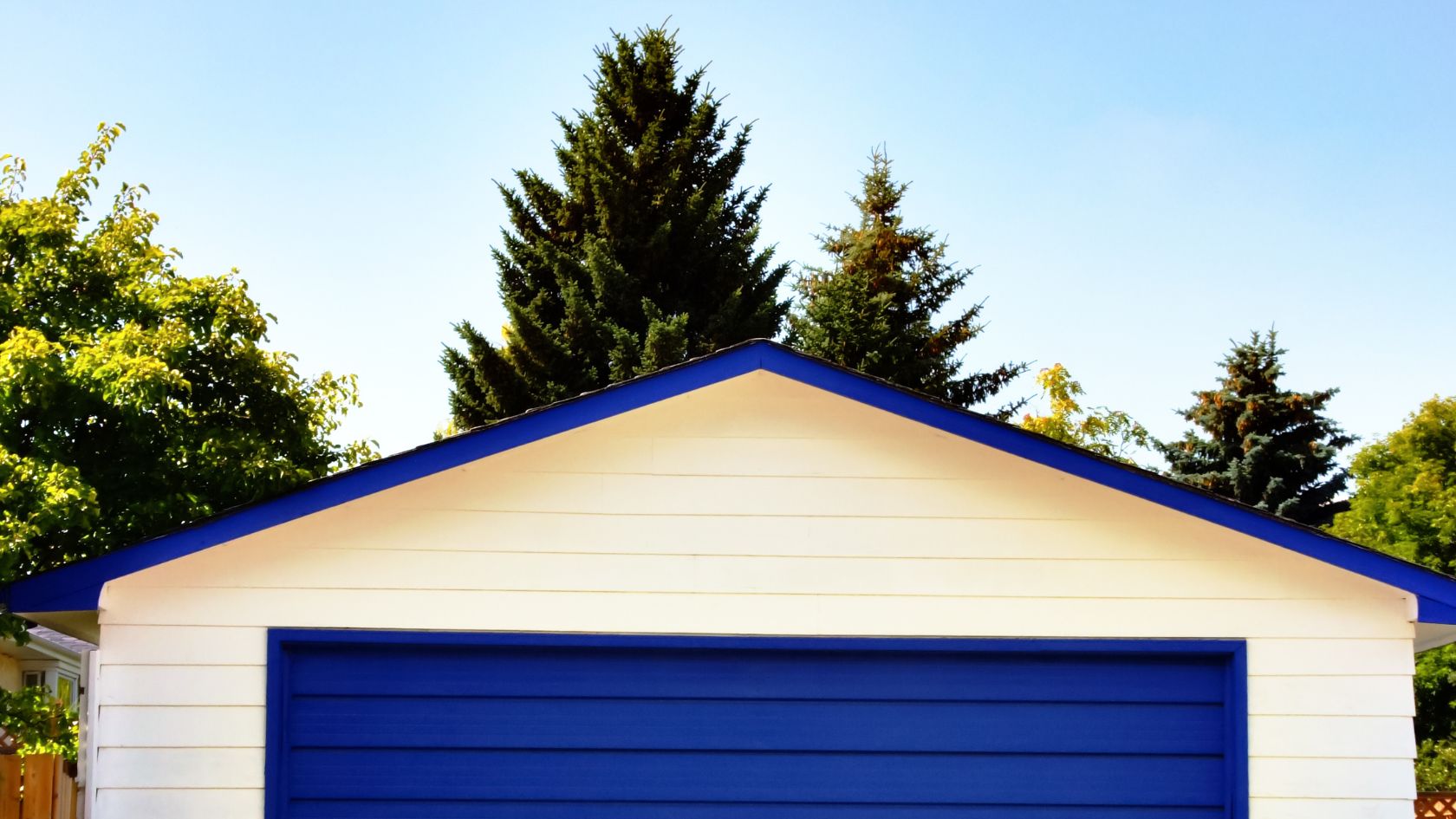 A blue and white garage with trees in the background