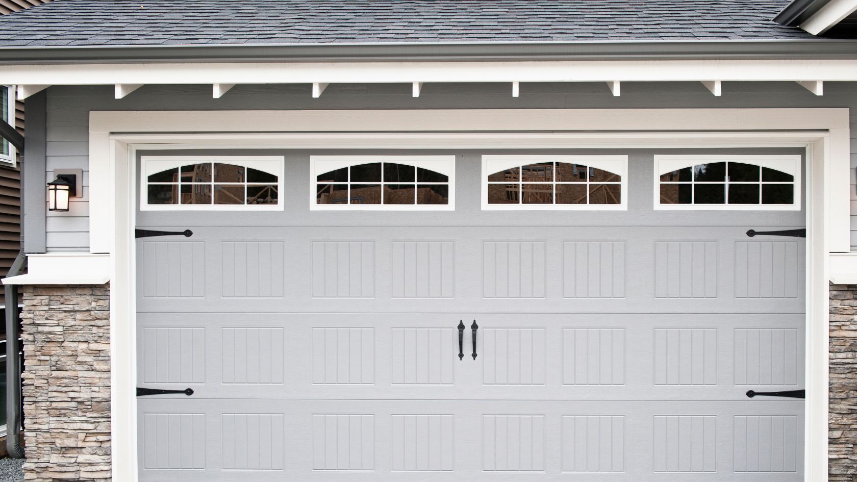 A gray garage door with windows on a house
